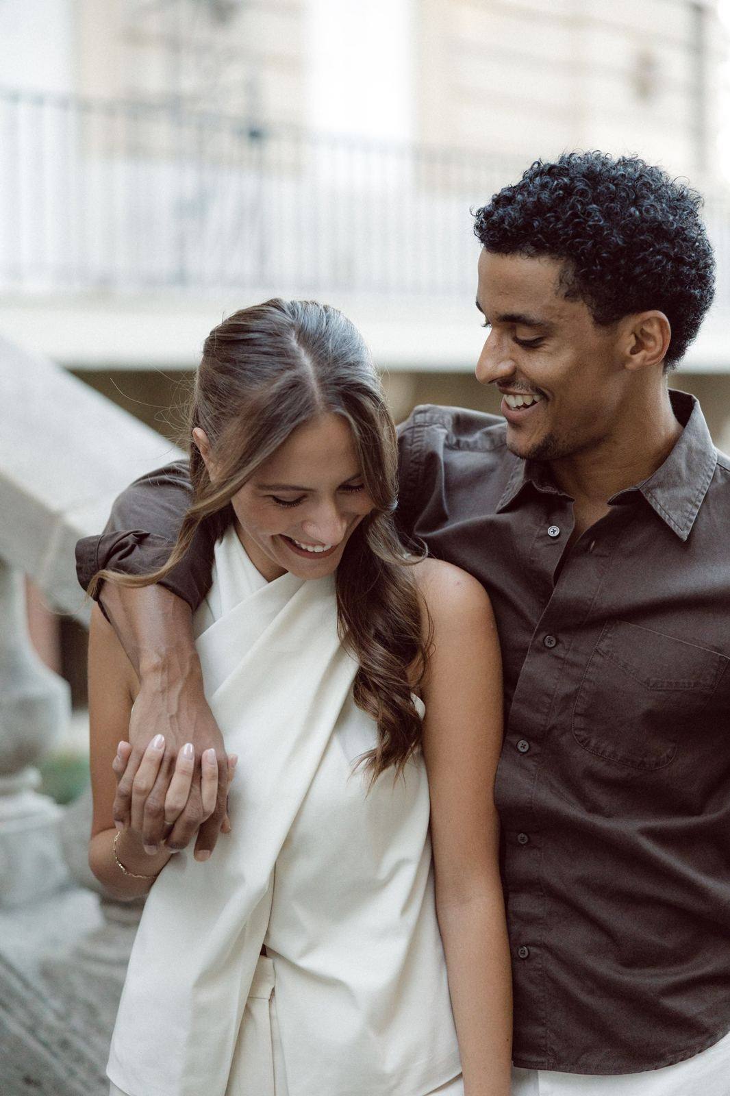 Couple laughing, his arm around her shoulders