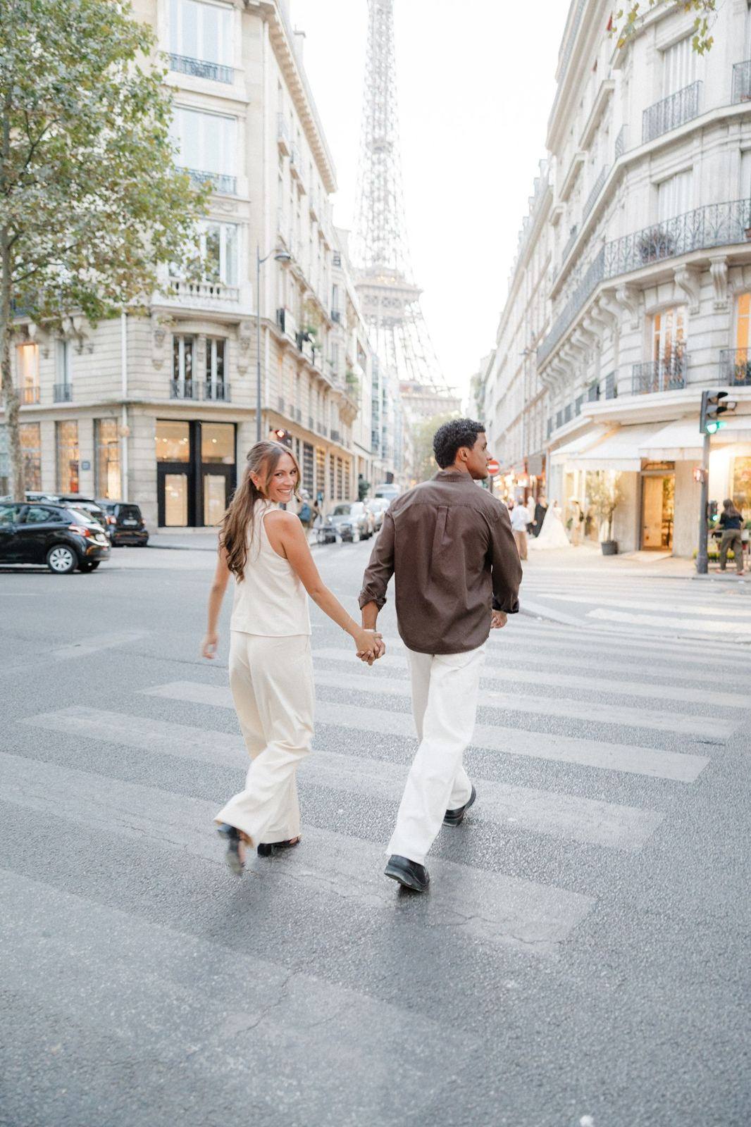 Couple crossing a Paris street, looking back at the camera