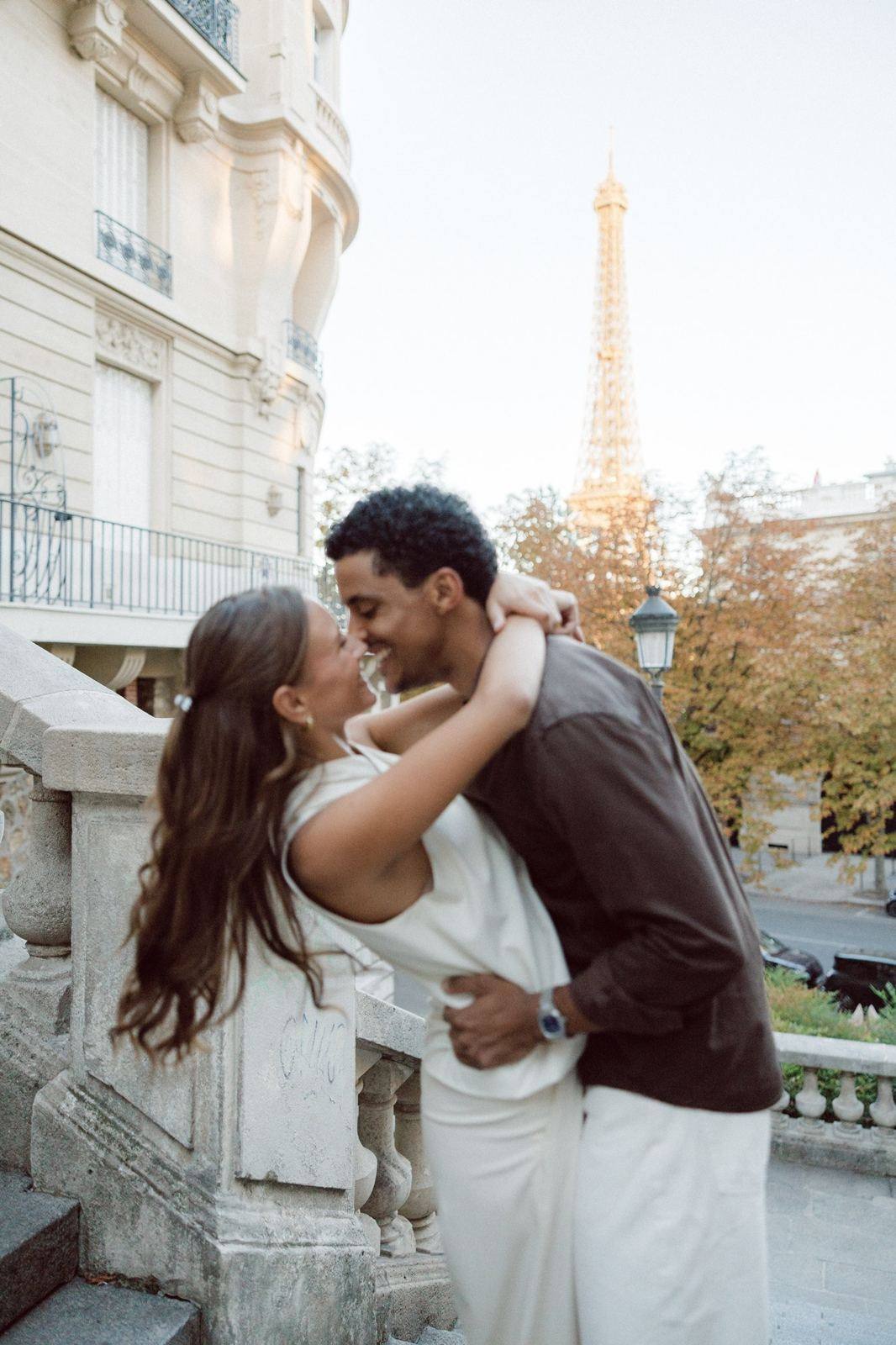Couple kissing on a stone staircase, the Eiffel Tower in the distance