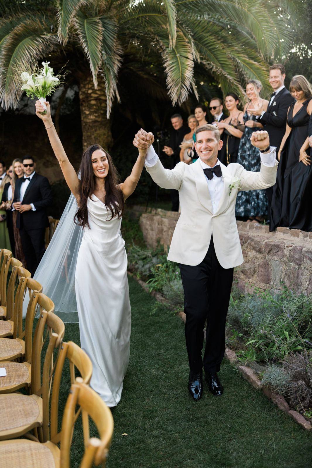 Newlyweds raising their arms as they leave the ceremony — wedding photographer in France