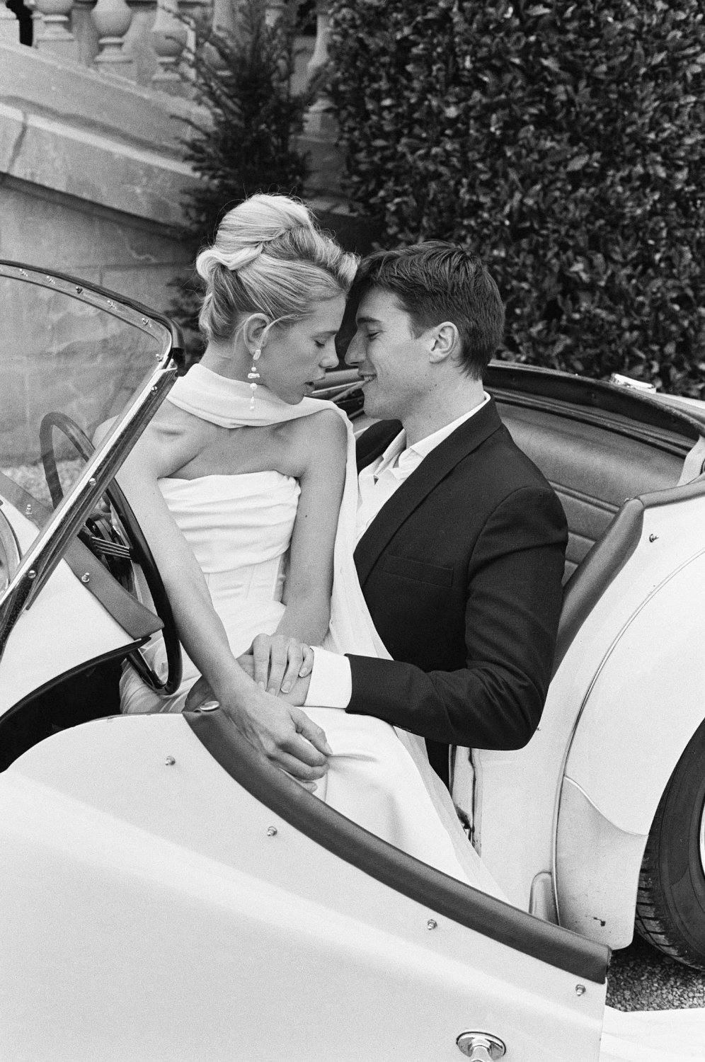 Bride and groom kissing in a vintage convertible, black and white film photograph