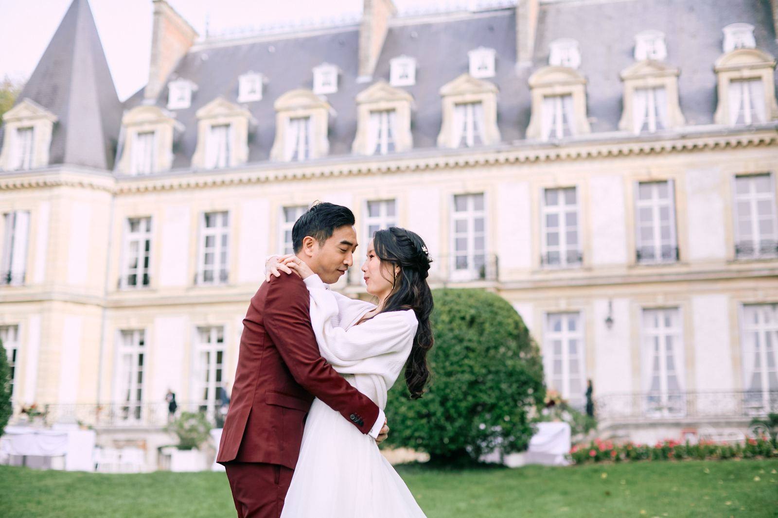 Groom in a burgundy suit in front of a château